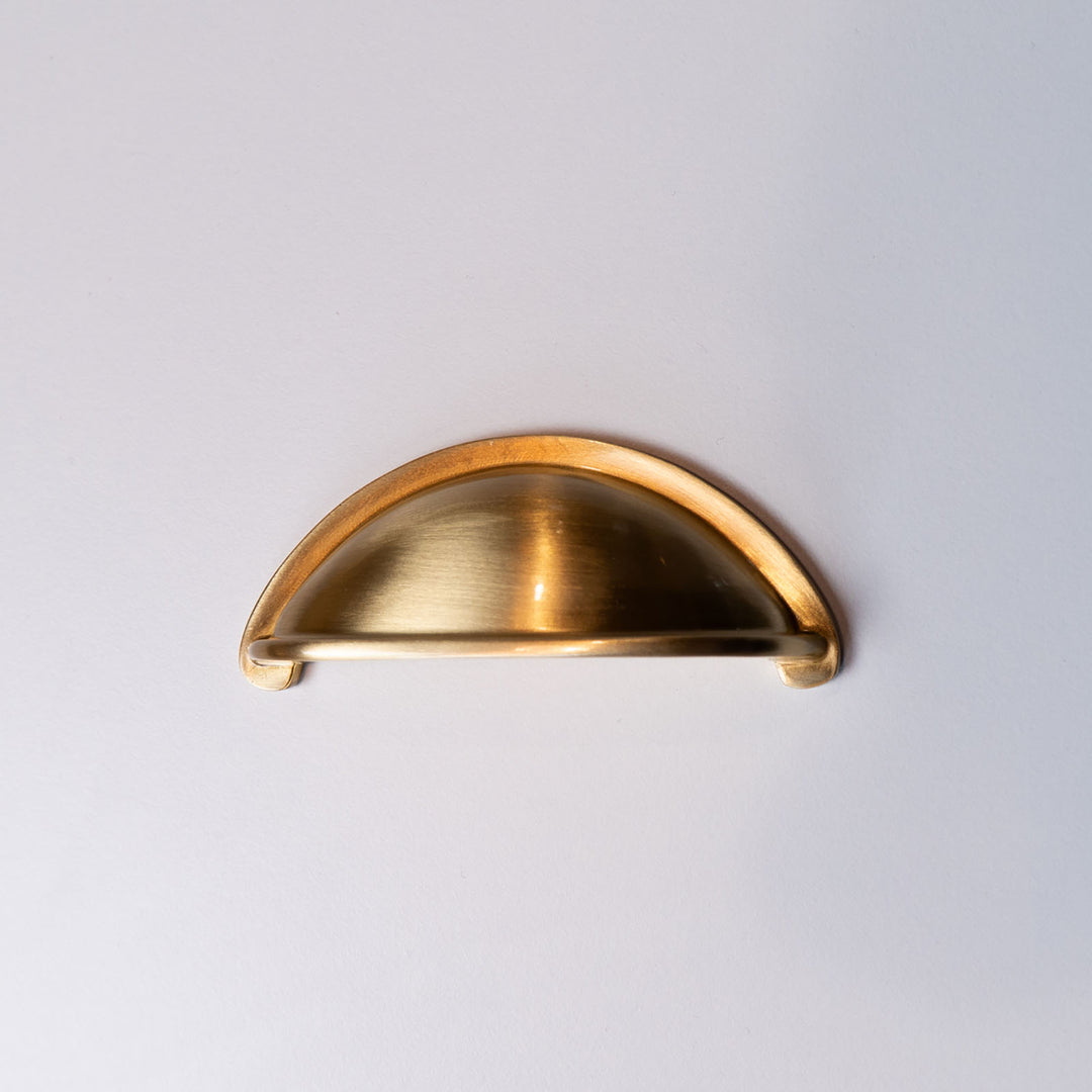 Gold cabinet handle on a light gray background